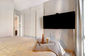 Habitación de hotel con una cama grande, un televisor de pantalla plana en la pared y una ventana con cortinas.