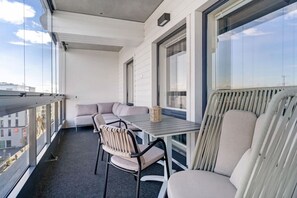 A balcony with a table and chairs, a sofa, and a view of the cityscape. - Aurora Sky Penthouse By Lapland Host (Rovaniemi)