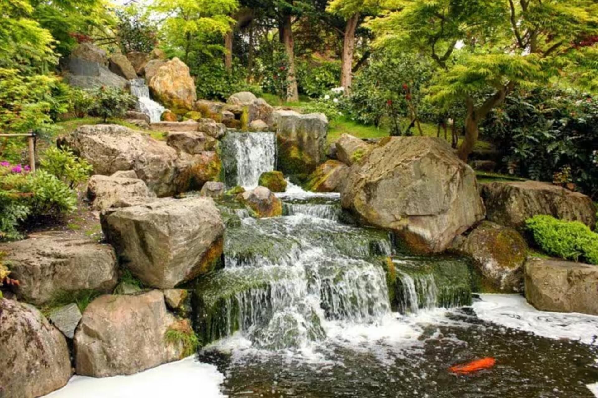 A waterfall surrounded by large rocks and lush greenery.