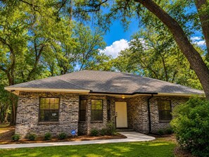 A single-story brick house with a gabled roof, a front door, and a small porch. - Lake Bluff Retreat (Marianna)