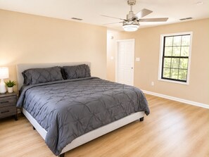 Ein Schlafzimmer mit Bett, Deckenventilator, Fenster und Tür.