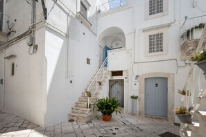 Une rue étroite avec un bâtiment blanc, un escalier et une plante en pot.