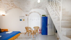 A room with a bed, two wicker chairs, a small table, a blue cabinet, and a staircase. - A cozy 48-square-meter apartment, ideal for two people, located on the first floor of a typical historic center home (accessible via stairs). The location is perfect: the property is right in the town center (within the ZTL/restricted traffic zone), with (Martina Franca)