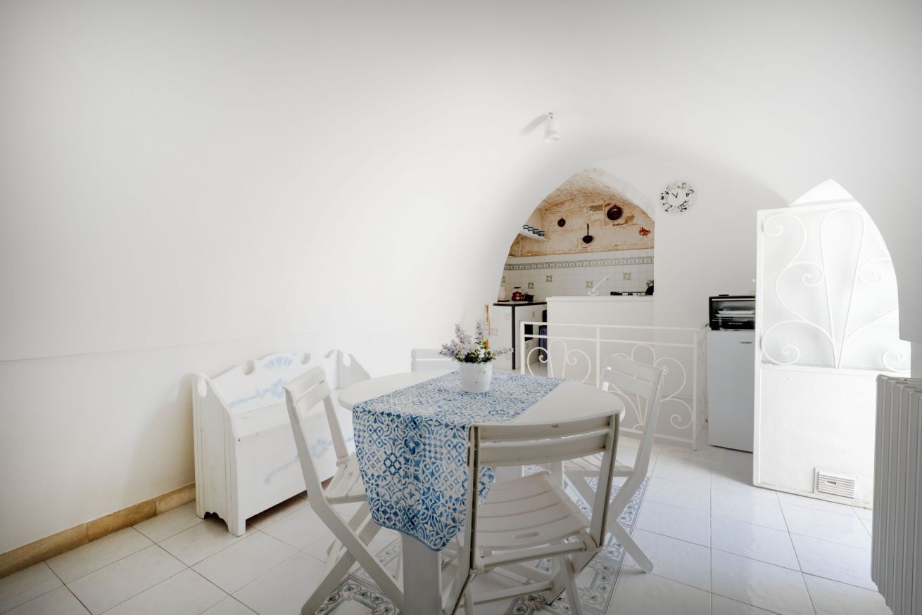 Un comedor blanco con una mesa lista para dos personas, un radiador blanco y un armario blanco.