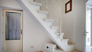 A staircase with white steps and a white railing, leading to a landing with a white box and a decorative wall piece. - A cozy 48-square-meter apartment, ideal for two people, located on the first floor of a typical historic center home (accessible via stairs). The location is perfect: the property is right in the town center (within the ZTL/restricted traffic zone), with (Martina Franca)
