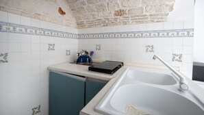 A kitchen with white tiles, a sink, and a dishwasher. - A cozy 48-square-meter apartment, ideal for two people, located on the first floor of a typical historic center home (accessible via stairs). The location is perfect: the property is right in the town center (within the ZTL/restricted traffic zone), with (Martina Franca)