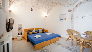 A bedroom with a bed, a chair, a table, and a radiator. - A cozy 48-square-meter apartment, ideal for two people, located on the first floor of a typical historic center home (accessible via stairs). The location is perfect: the property is right in the town center (within the ZTL/restricted traffic zone), with (Martina Franca)