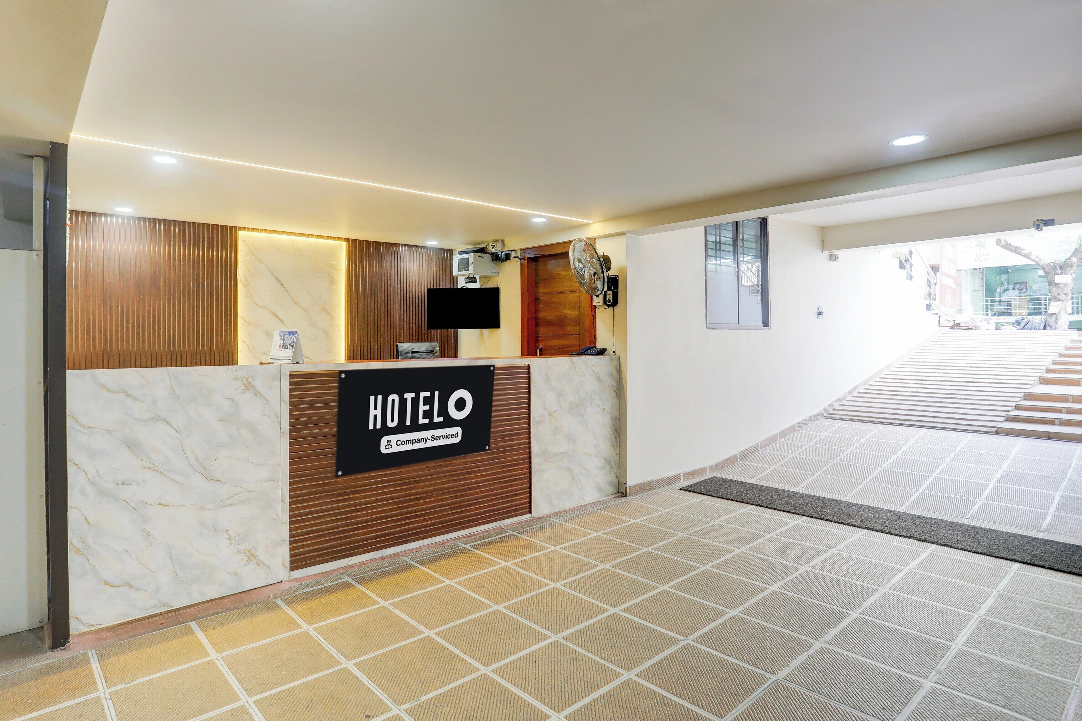 Et hotelreceptionsområde med en marmorindskrivningsdisk, en træpanelfod, et fladskærms-tv og et skilt der angiver, at hotellet er servicespecifikt.