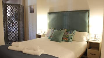 Una cama bien hecha con un cabecero azul, almohadas blancas y una manta gris.