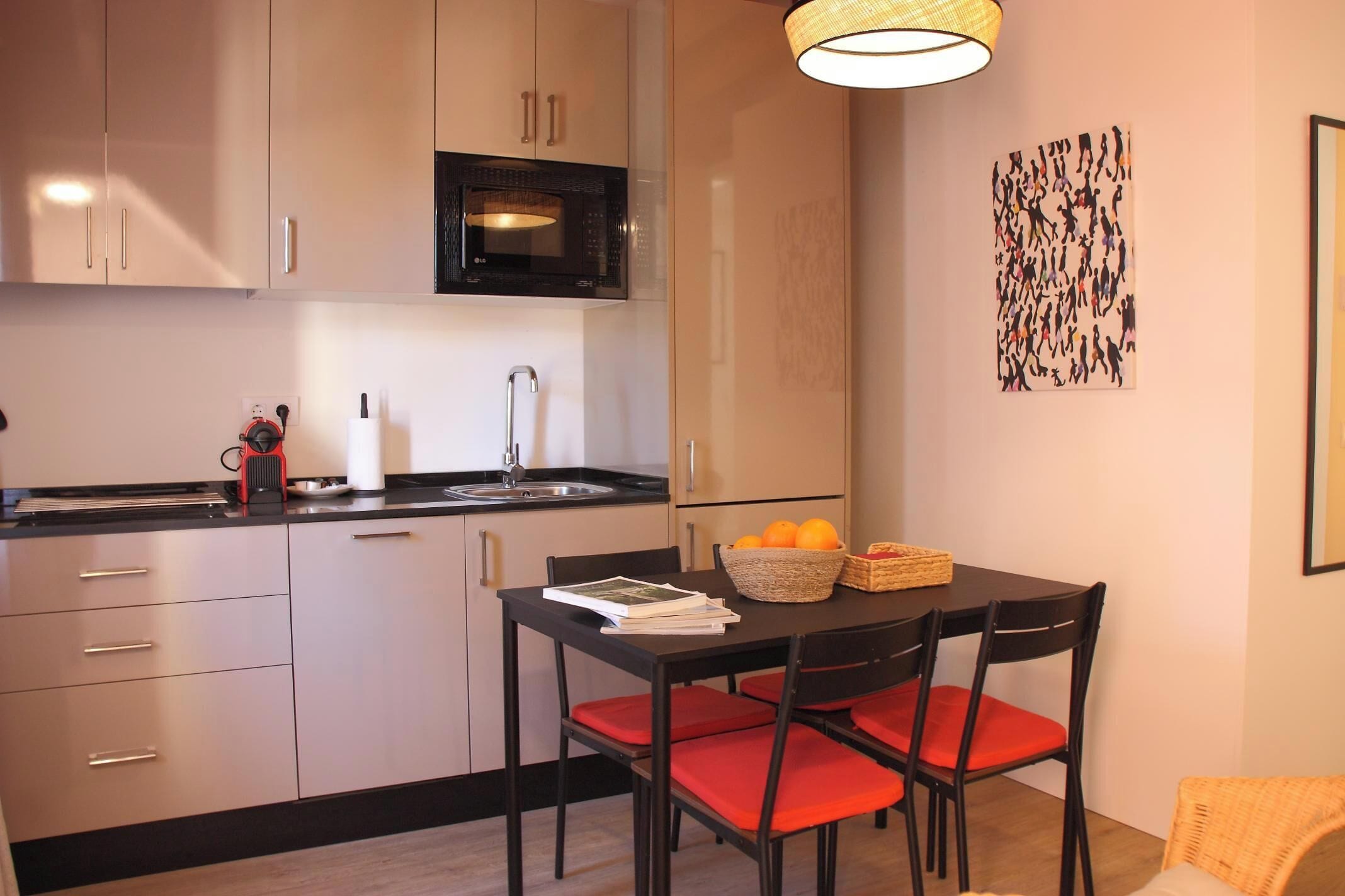 Una cocina moderna con comedor, que incluye microondas, pileta y una mesa con sillas.