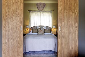 A bedroom with a bed, curtains, a hanging light fixture, and bedside lamps. - Luxury Converted Stable Cottage | Lake District | EV Charger & Private Patio (Carnforth)
