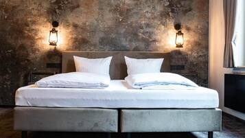 A bed with two pillows and a headboard, flanked by two wall-mounted light fixtures.