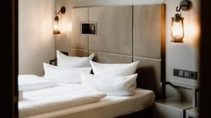 Una habitación de hotel moderna con una cama grande, lámparas de noche y una mesita de noche pequeña.