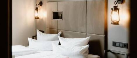 Ein modernes Hotelzimmer mit einem großen Bett, Nachttischlampen und einem kleinen Nachttisch.