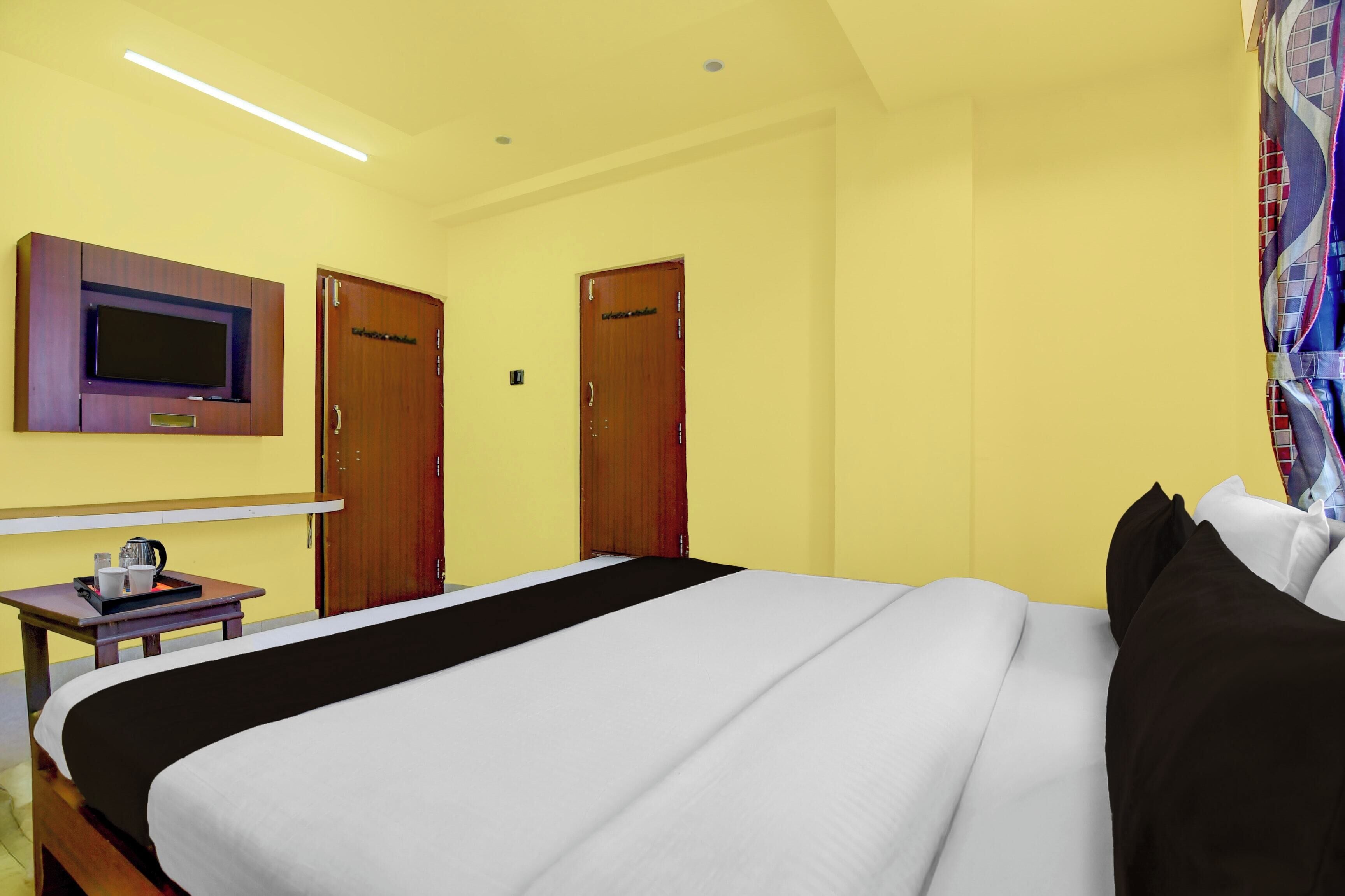 A hotel room with a bed, a TV mounted on the wall, and two doors.