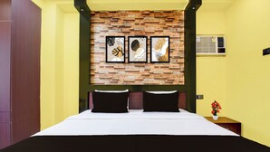 Habitación de hotel con cama, aire acondicionado de pared y una mesita de noche con un jarrón de flores.