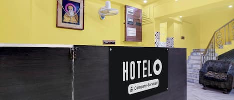 A hotel reception desk with a sign indicating it is a company-serviced hotel.