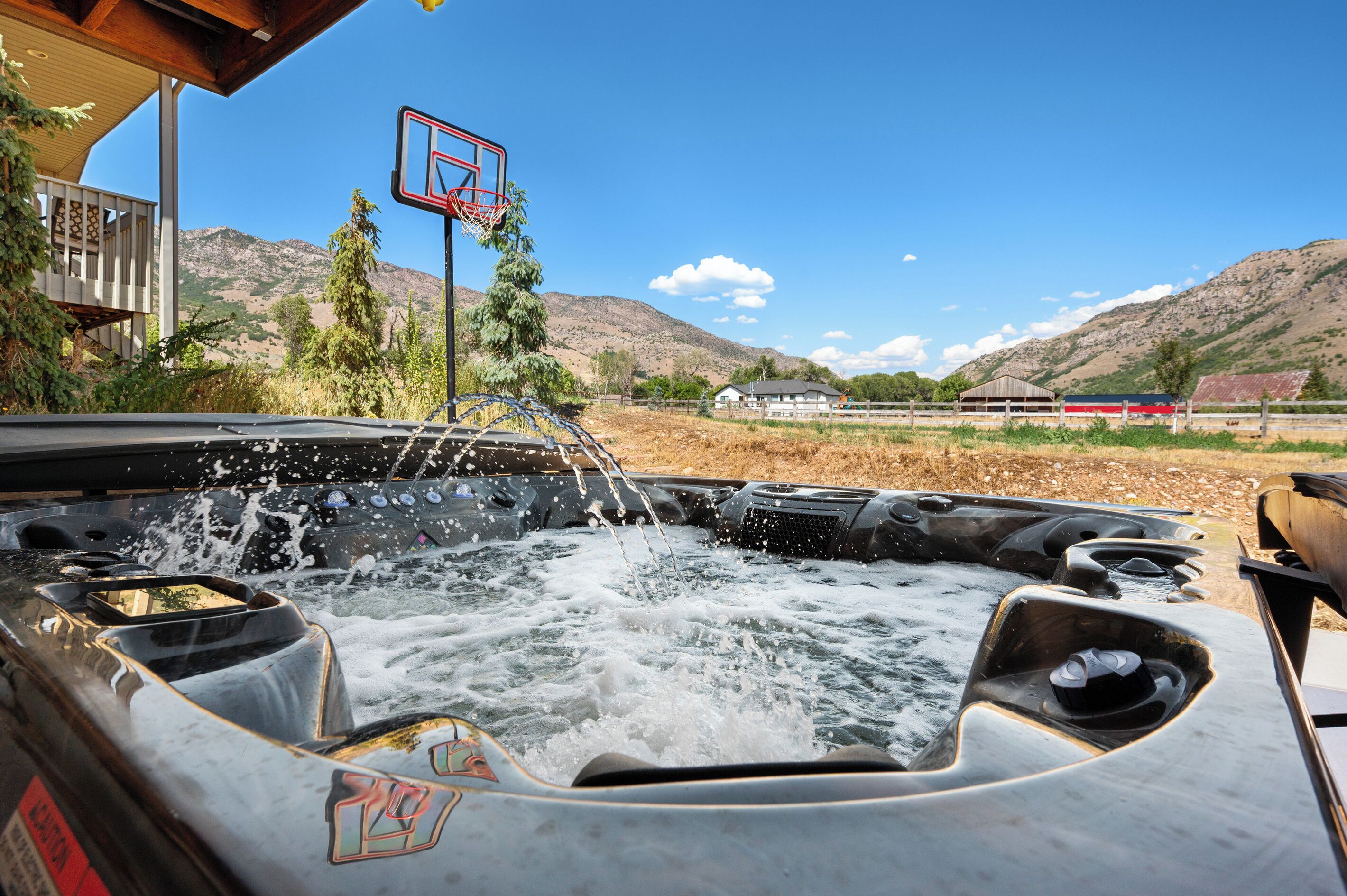 Un jacuzzi con chorros de agua, una canasta de baloncesto y un paisaje montañoso al fondo.