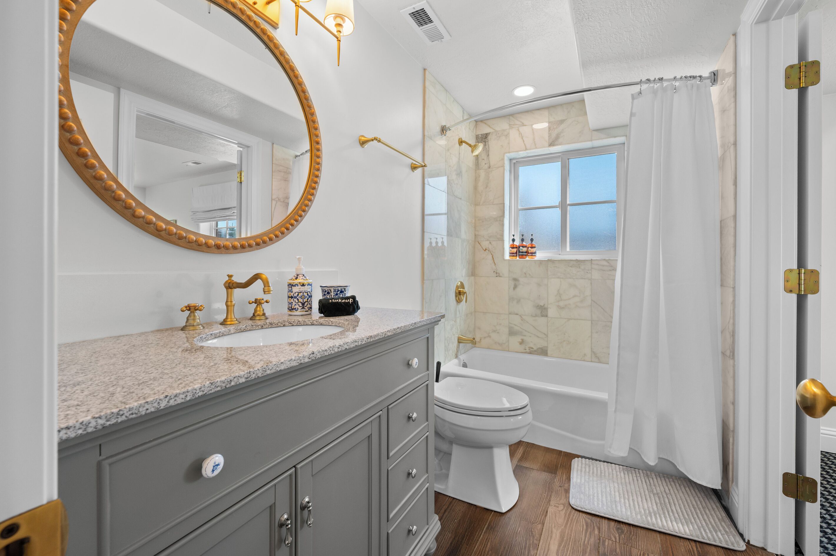 A bathroom with a vanity, sink, mirror, toilet, bathtub, and shower curtain.