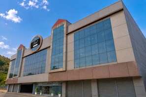 Un edificio moderno con una amplia fachada de vidrio, un llamativo letrero circular y un techo plano.