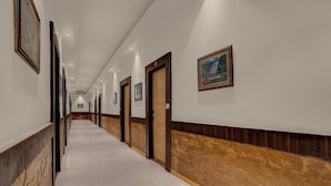 Un largo pasillo con puertas a un lado y una pared de mármol al otro.