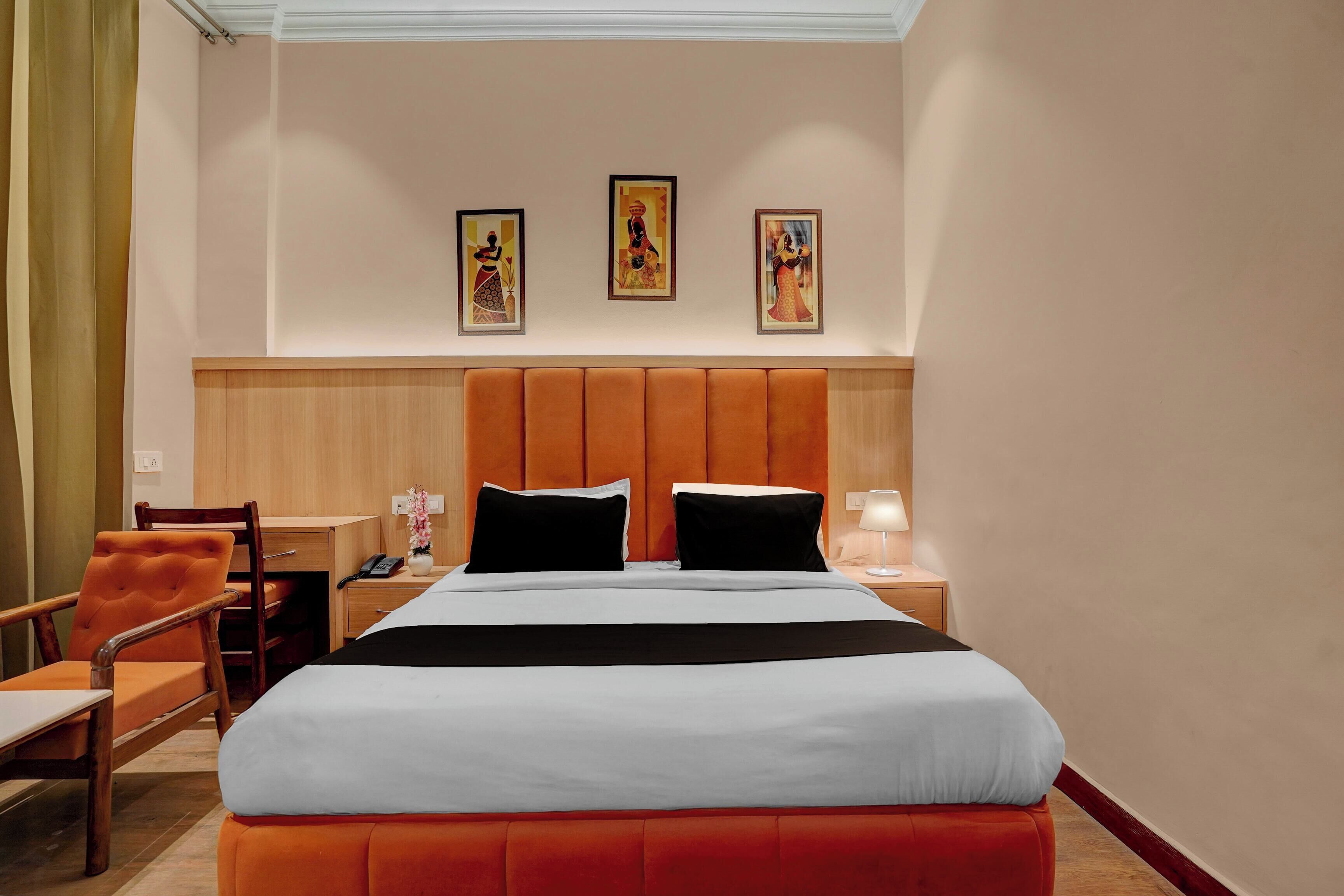 Una habitación de hotel con una cama, un escritorio, una silla y tres cuadros en la pared.