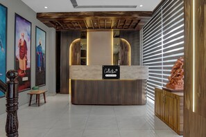 A reception area with a wooden reception desk, a 'Collection' sign, and a statue on the right.