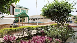 A landscaped outdoor area with a pool, a covered seating area, and a variety of plants. - Loreto Palm Villa: 17 en-suite AC rooms with on-site restaurant (Cape Coast, Ghana)