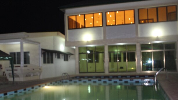 A building with a swimming pool, large windows, and a covered area. - Loreto Palm Villa: 17 en-suite AC rooms with on-site restaurant (Cape Coast, Ghana)
