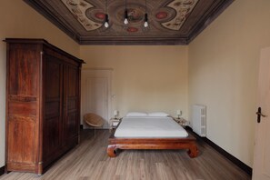 Ein Schlafzimmer mit einem hölzernen Bett, einem Schrank, einem Stuhl und einer Decke mit Zierleisten.