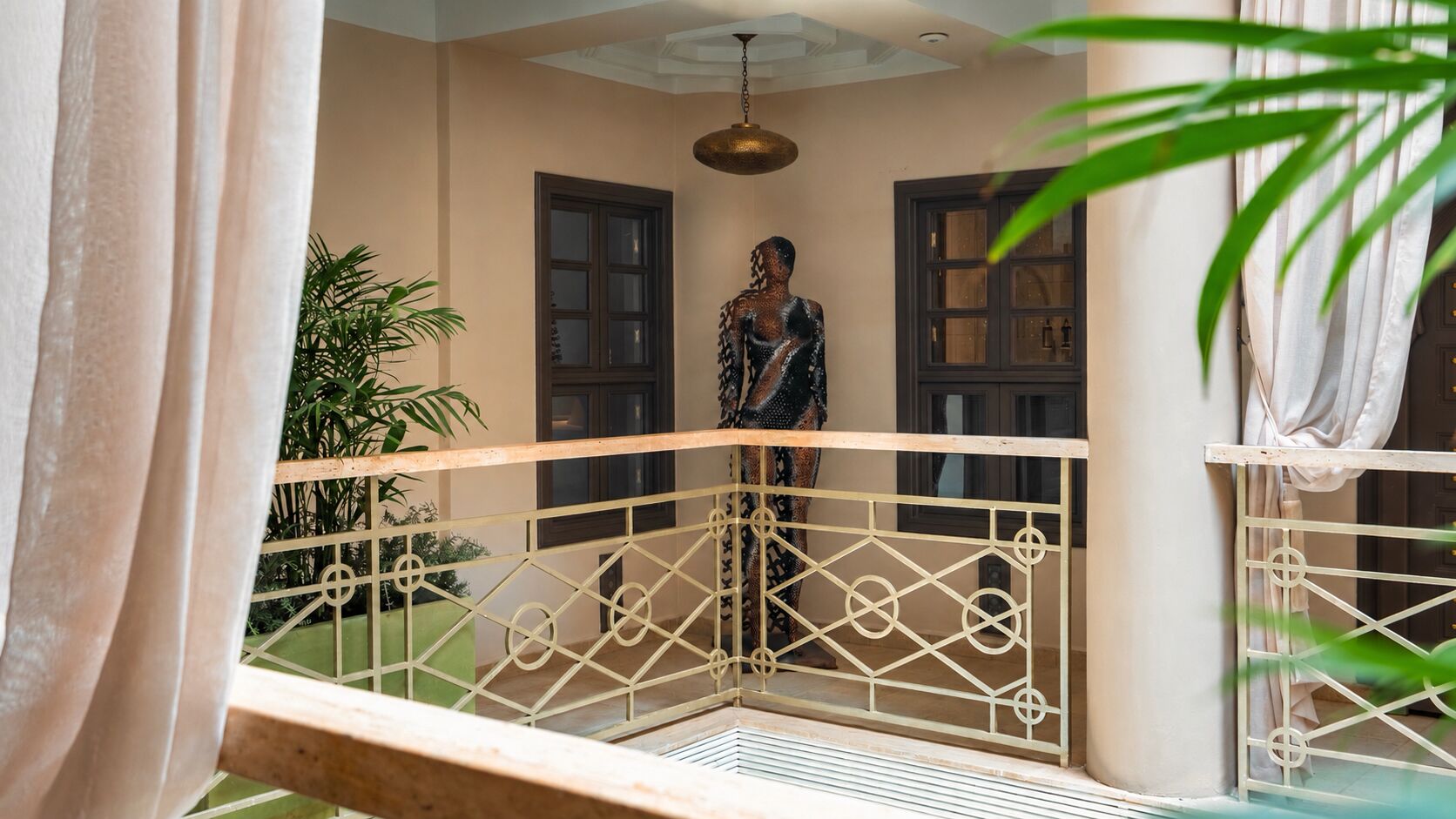 Ein Balkon mit Metallgeländer, einer Statue und einem Blumentopf.