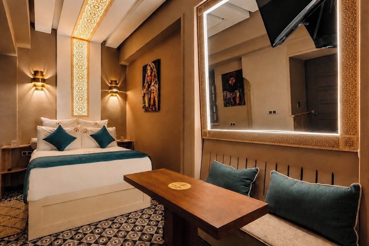 Une chambre d’hôtel avec un lit, des lampes de chevet, une table et un miroir.