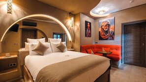Une chambre d’hôtel avec un grand lit, un canapé rouge et deux tableaux accrochés au mur.