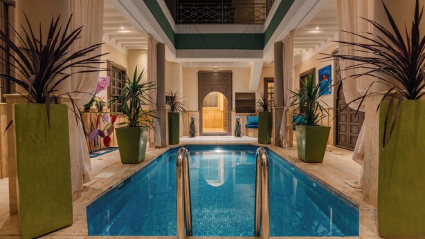 A pool area with a clear view of the pool, surrounded by potted plants and a wooden deck. - Riad Chouïa-Chouïa (Marrakech)