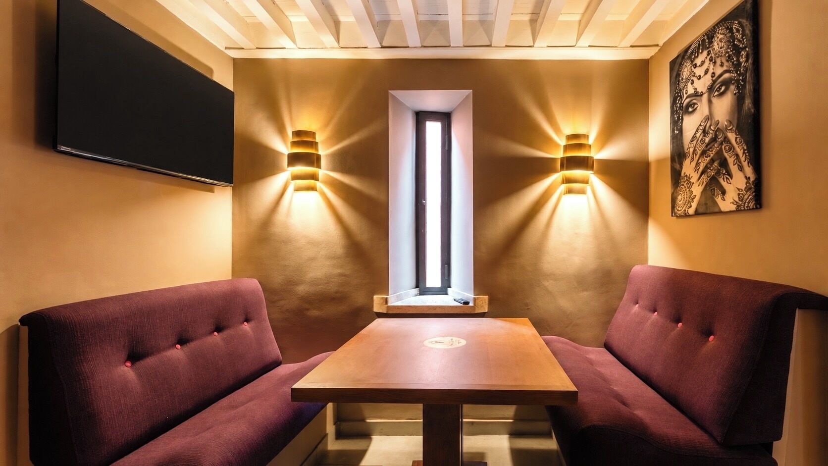 Ein Zimmer mit zwei Sitzgelegenheiten, einem Holztisch und Wandleuchten.