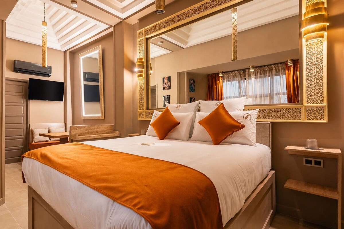 Une chambre d’hôtel avec un grand lit, une télévision, un miroir et des panneaux muraux décoratifs.