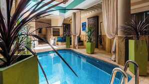 An indoor swimming pool with a clear view of the pool area, surrounded by potted plants and wooden furniture. - Riad Chouïa-Chouïa (Marrakech)