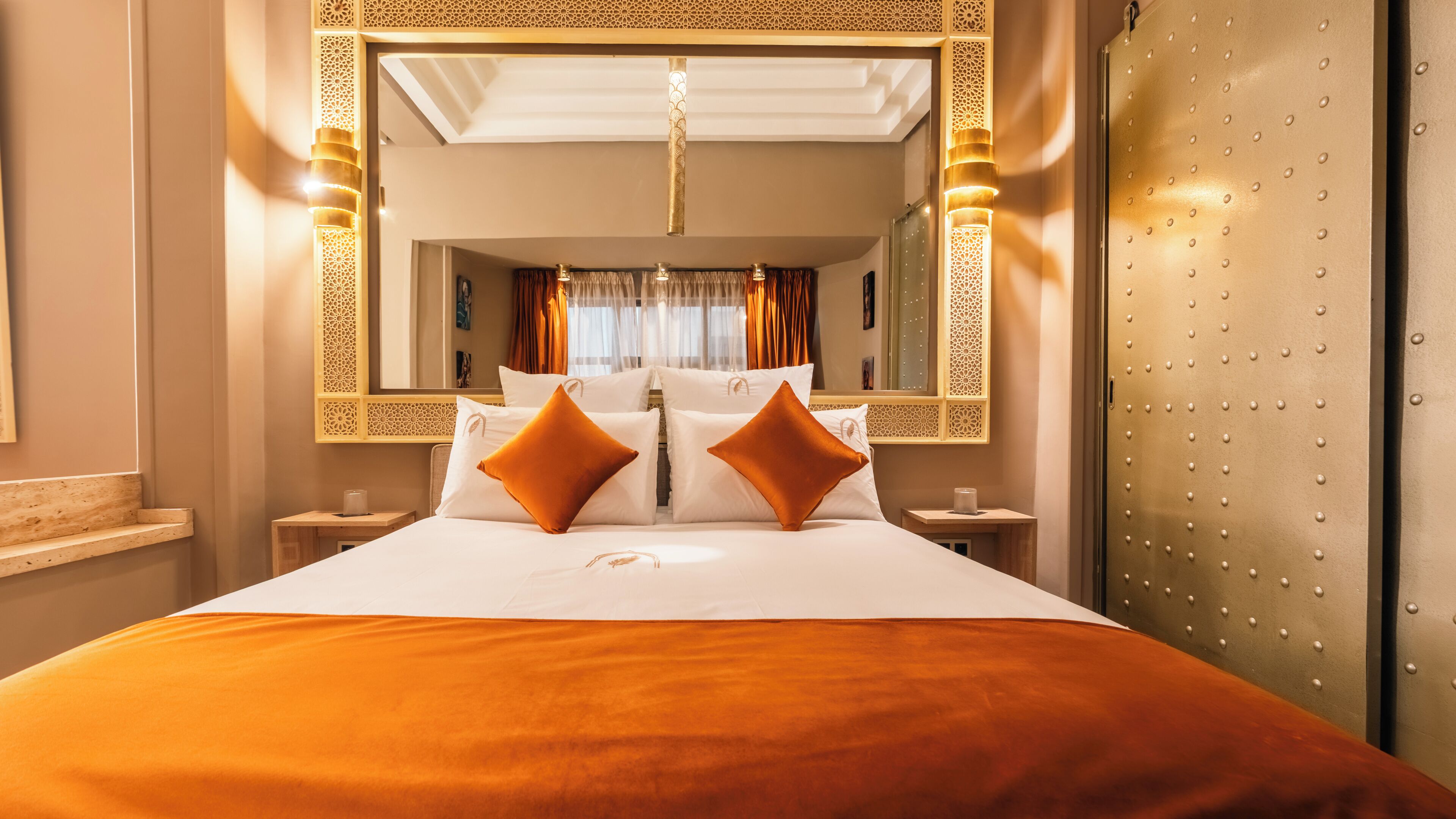 Ein Hotelzimmer mit einem großen Bett, zwei Nachttischen, einem Spiegel mit Zierrahmen und einem Schrank mit Metalloptik.
