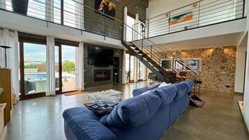 Un amplio salón con un sofá azul, una chimenea y una escalera que sube a un nivel superior.
