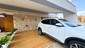 A white SUV parked in a covered parking area with a stone wall and a tiled floor.