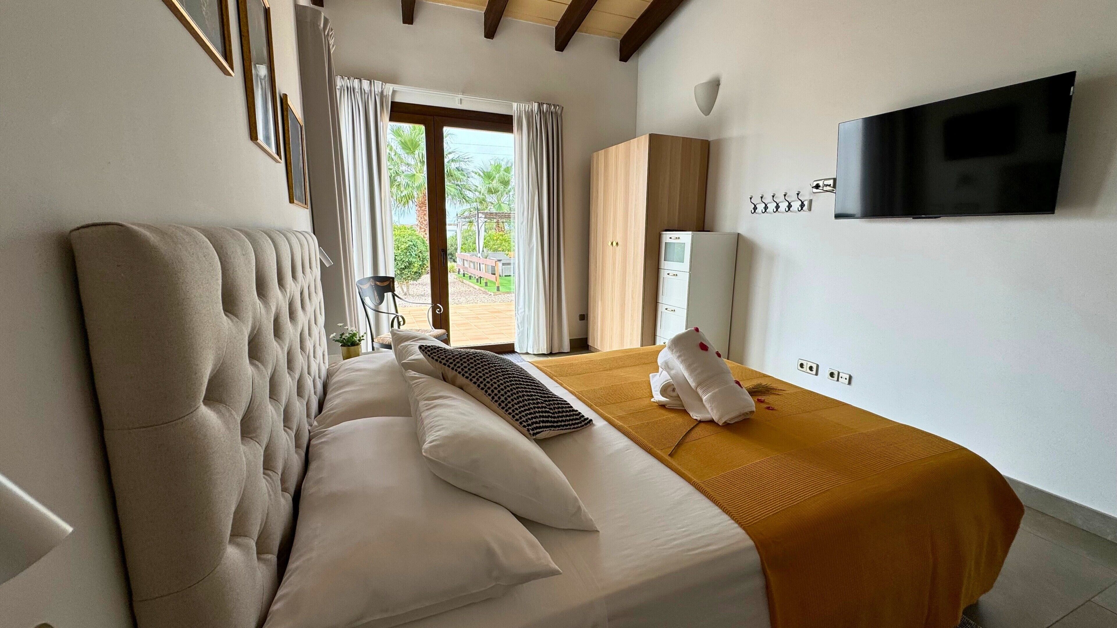 A hotel room with a large bed, a television mounted on the wall, and a view of the outdoors through the window.