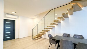 Ein modernes Interieur mit einer Treppe, einem Essbereich und einer Tür.