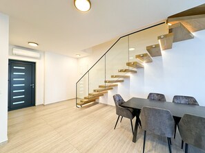 Ein modernes Interieur mit einer Treppe, einem Essbereich und einer Tür.