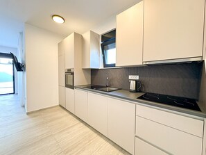 Eine moderne Küche mit integrierten Geräten, einem Fenster und Blick ins Freie.
