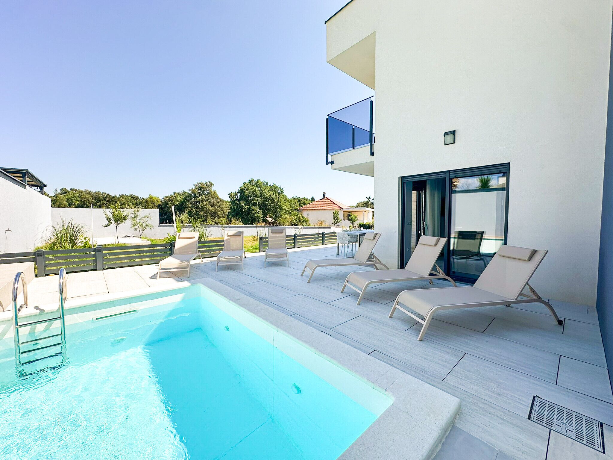 A modern outdoor pool area with lounge chairs and a clear blue pool.