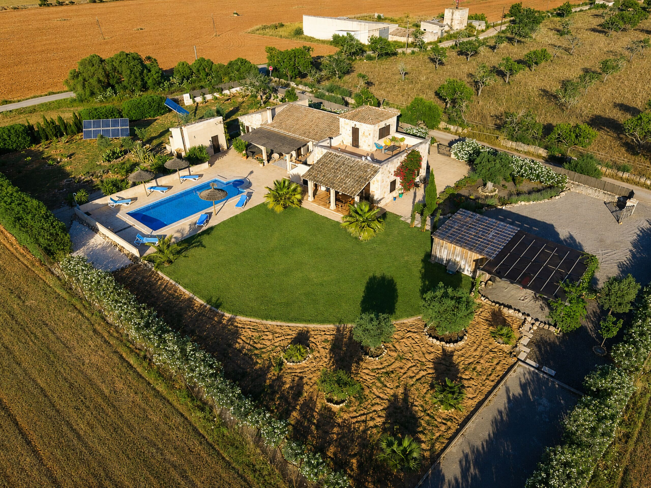 Vue aérienne d’une propriété dotée d’une piscine, de panneaux solaires et d’une pelouse bien entretenue.