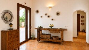 A room with a wooden cabinet, a table with decorative items, and a wall with wall sconces and wall art. - Canyop, 5StarsHome Villa, Mallorca (Campos)