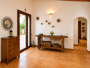 Ein Zimmer mit einem Holzkabinett, einem Tisch mit Dekoration und einer Wand mit Wandleuchten und Wandkunst.