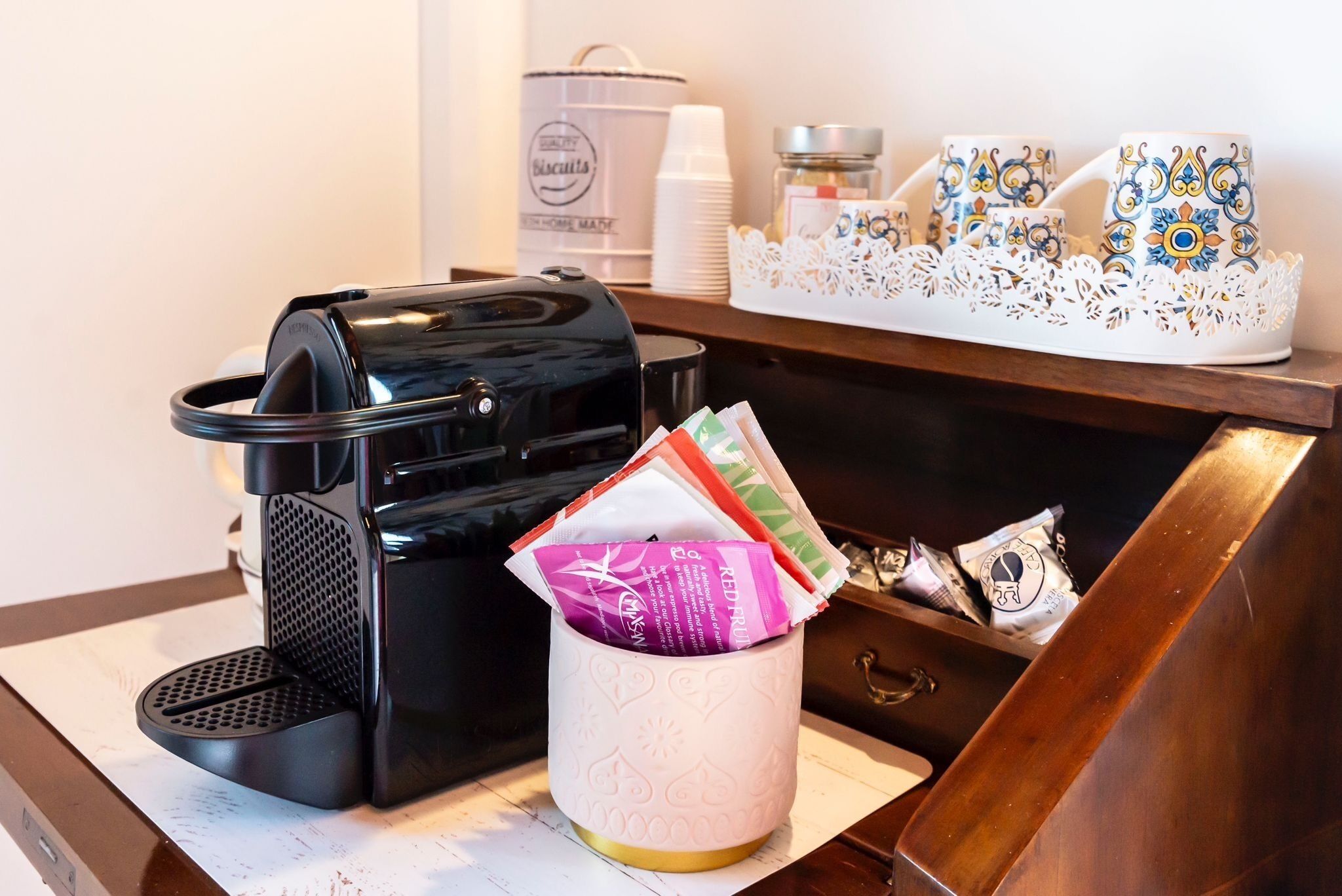 Une machine à café, un panier contenant des produits emballés et un tiroir avec un plateau décoratif.