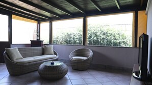 Una habitación con sofá, dos sillones, una mesita y televisor.